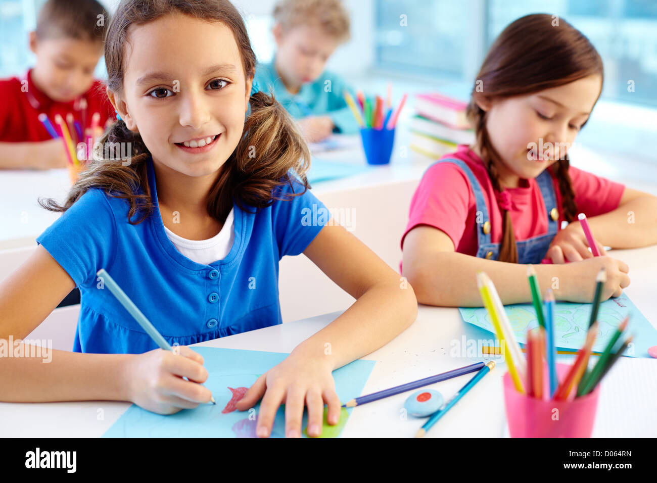 Portrait of lovely girl drawing at workplace and looking at camera with ...