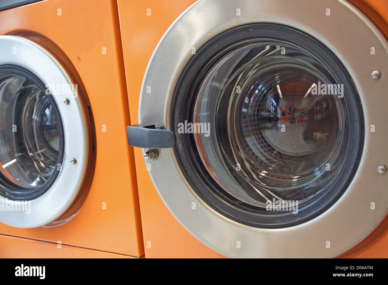 orange automatic washing machines in a laundromat Stock Photo