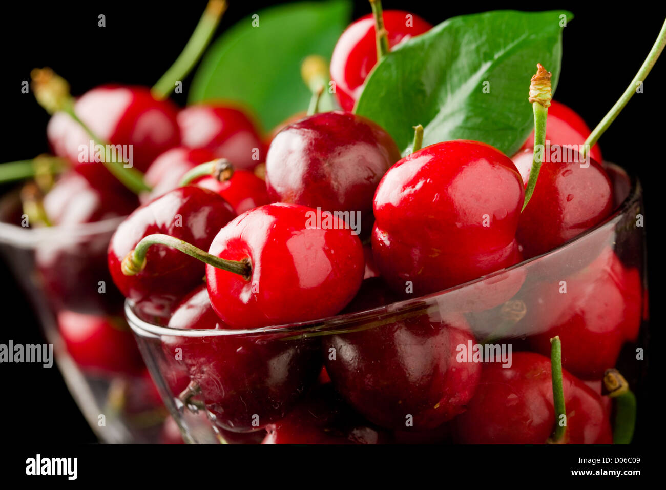 photo glass with cocktail cherries in front of black isolated