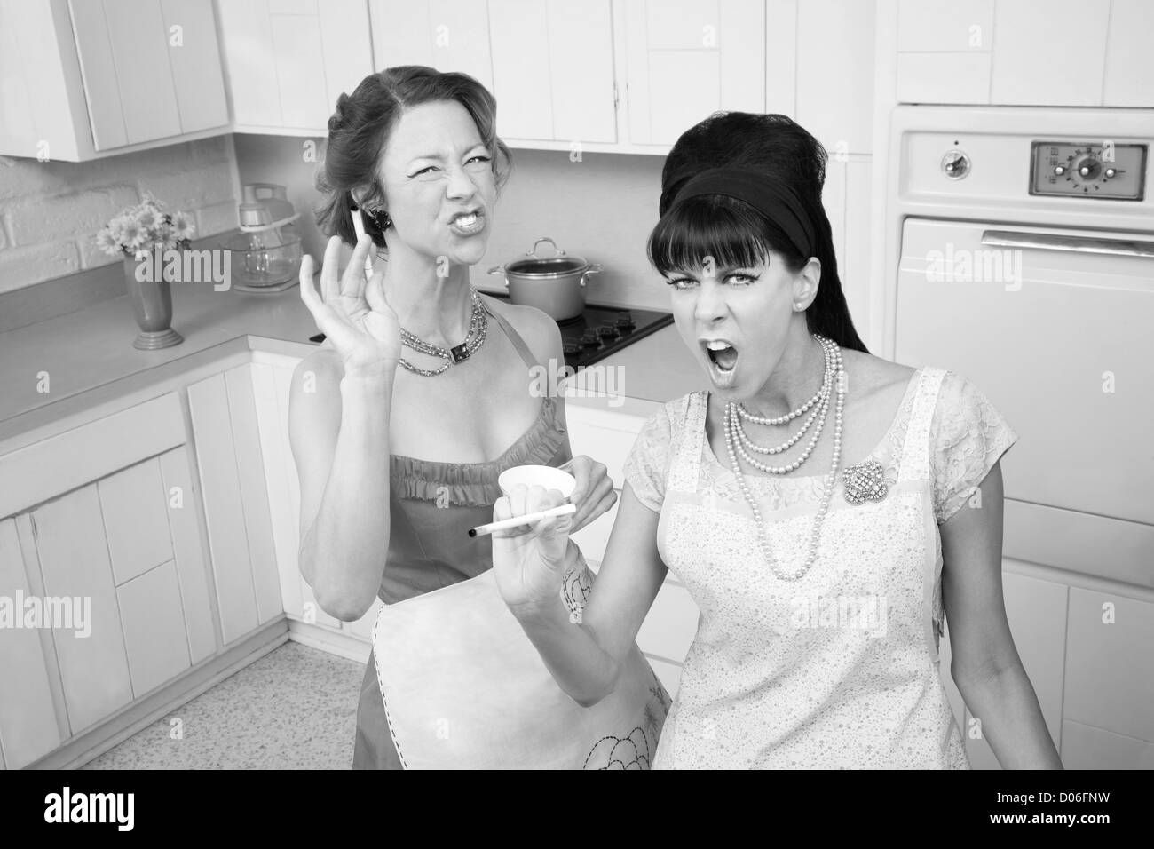 Two sassy housewives smoking cigarettes in the kitchen Stock Photo