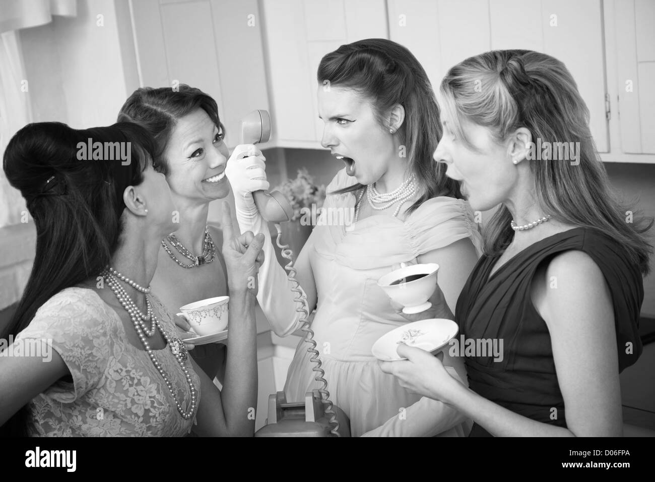 Angry woman on phone with three friends in a kitchen Stock Photo