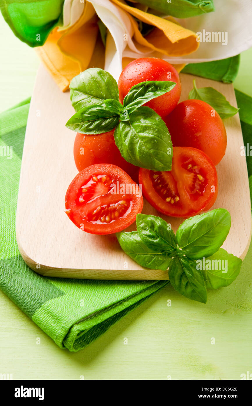 photo of sliced cherry tomatoes with basil on wooden cutting board ...
