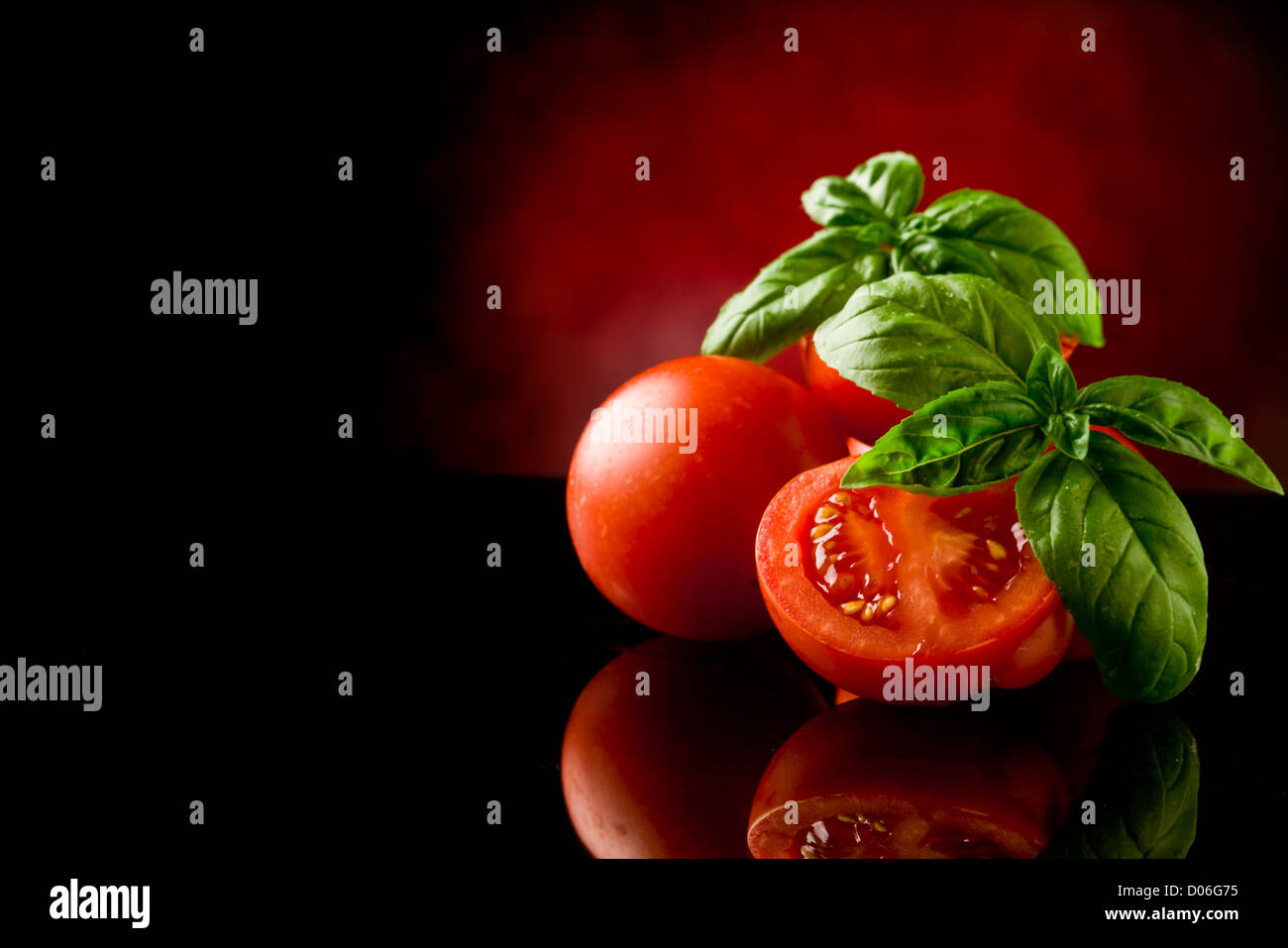 photo of fresh sliced tomatoes with basil on glass table with spot ...