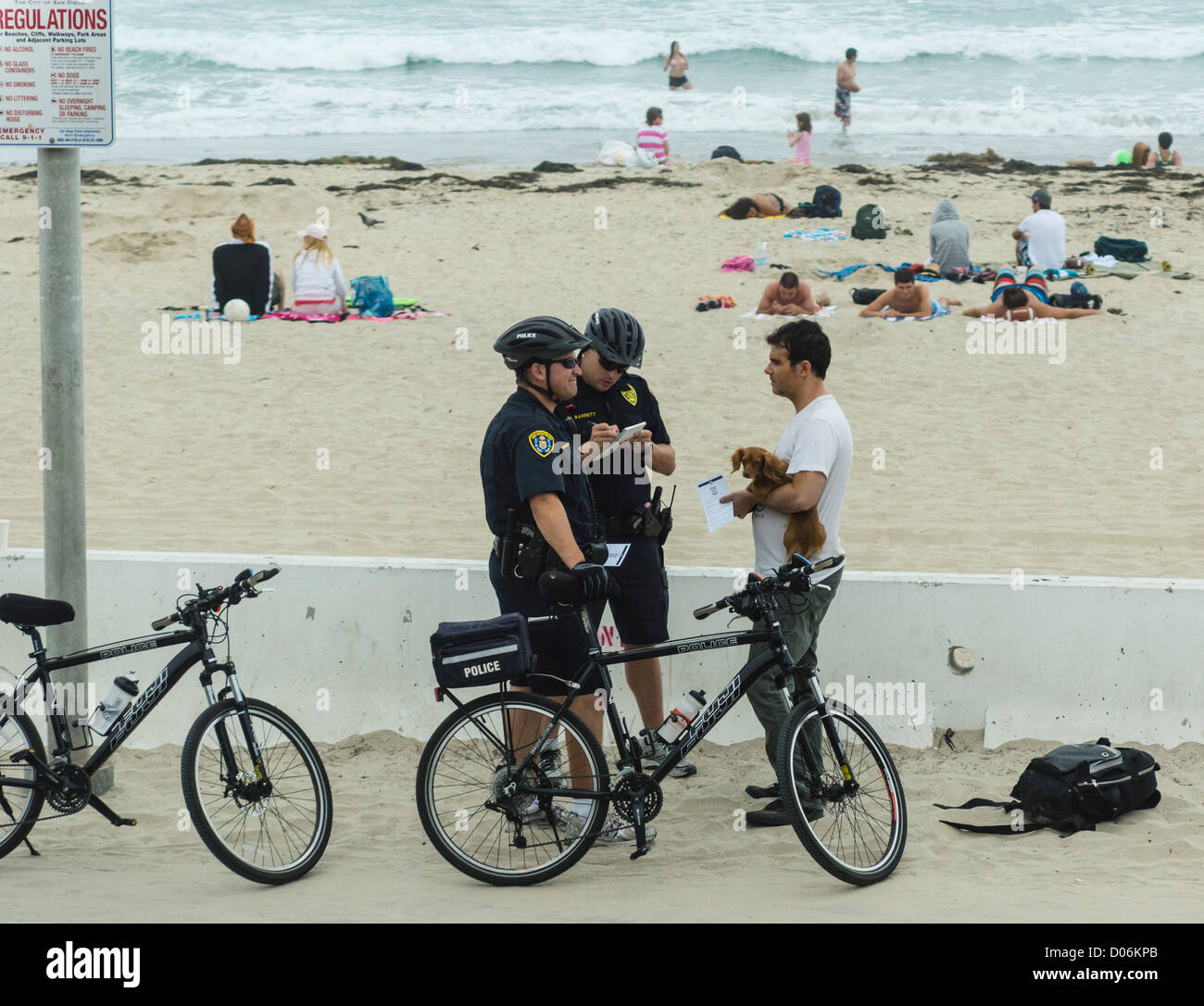 Pacific Beach, San Diego - no dogs on Pacific Beach. Cycle cop patrol gives a notice to dog owner. Stock Photo