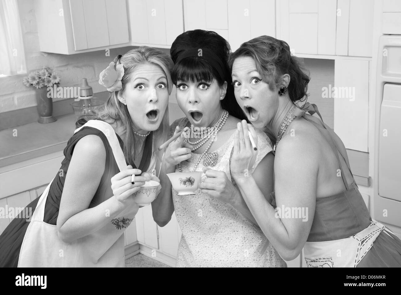 Three surprised middle-aged 1950s retro-style women with cigarettes and tea Stock Photo