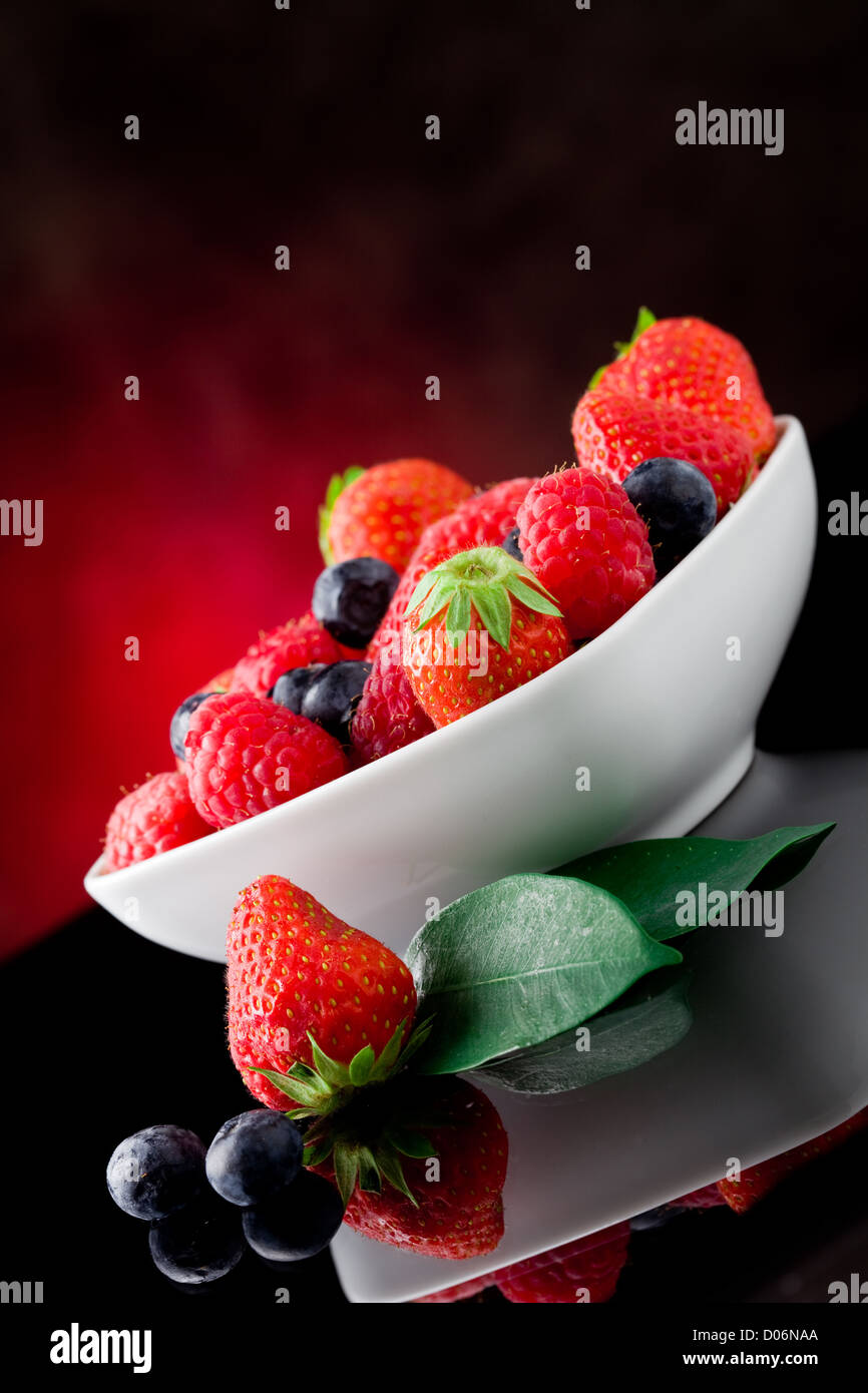 photo of mixed fresh berries on red lighted background Stock Photo Alamy
