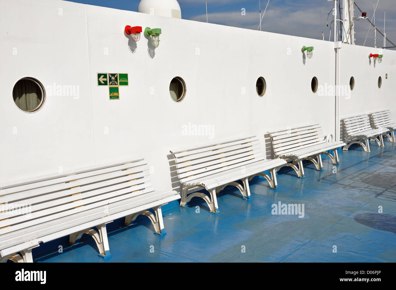 Row of benches and portholes on ship deck painted with white and blue colors. Stock Photo