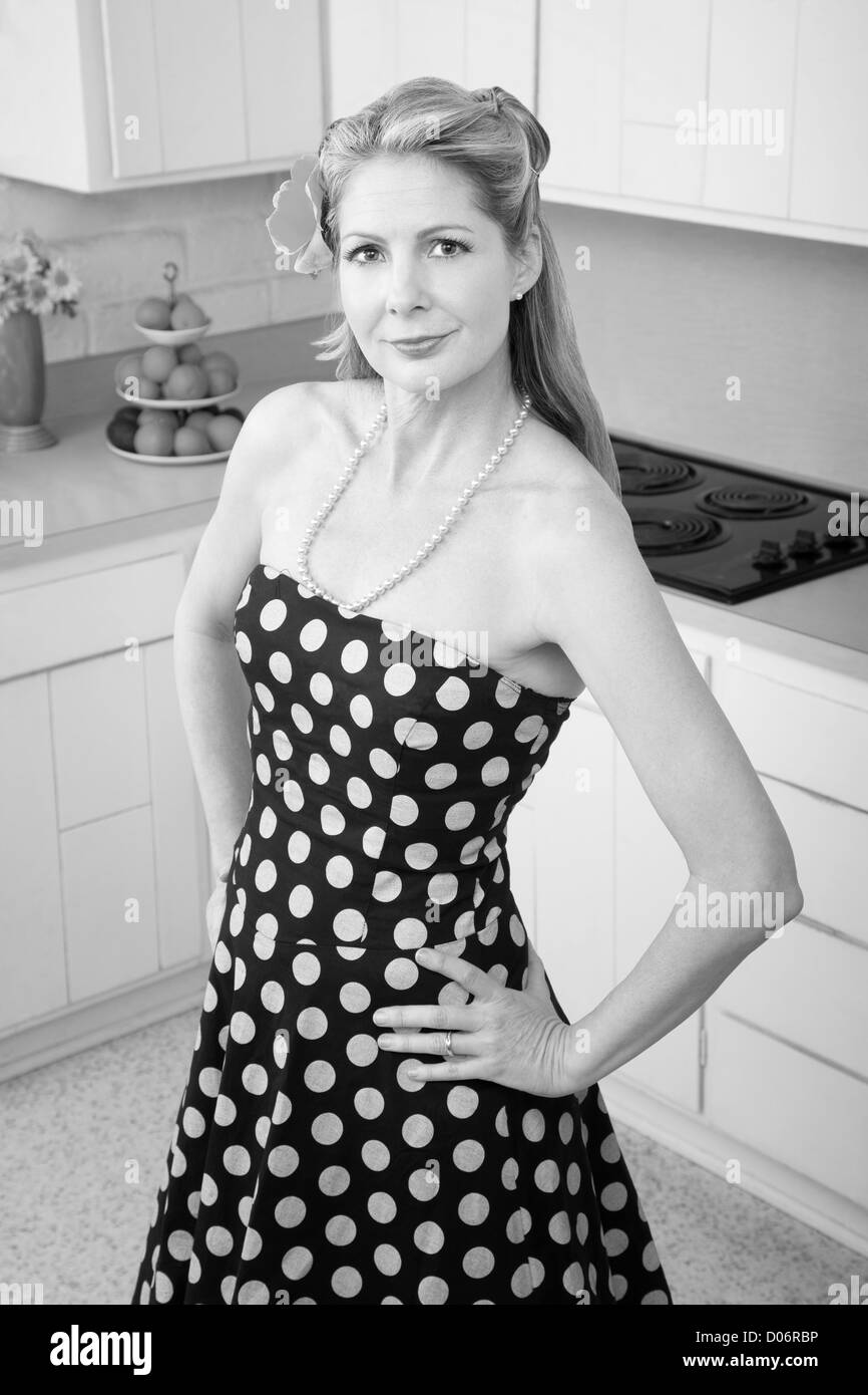 Confident Caucasian woman with hand on hips in kitchen Stock Photo