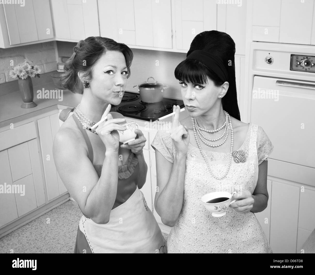 Two retro-styled women smoking cigarettes in a kitchen Stock Photo