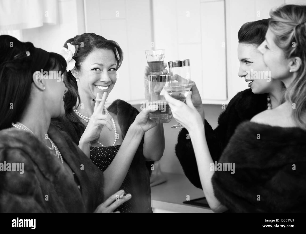 Group of four Caucasian women in a kitchen make a toast Stock Photo
