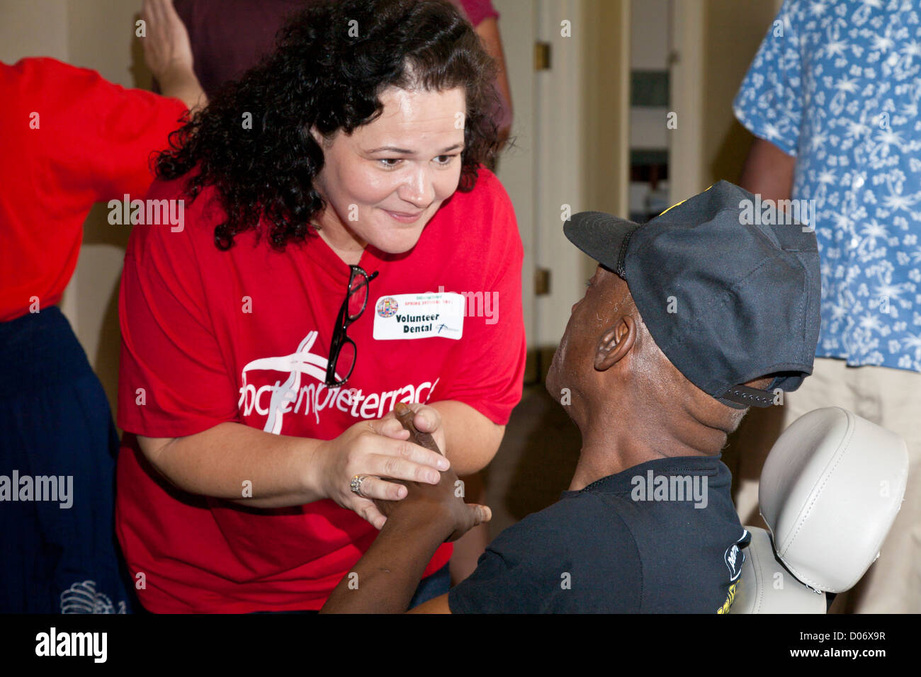 Female volunteer provides spiritual support for patients at Mission Smiles mobile dental clinic in Temple Terrace, FL Stock Photo