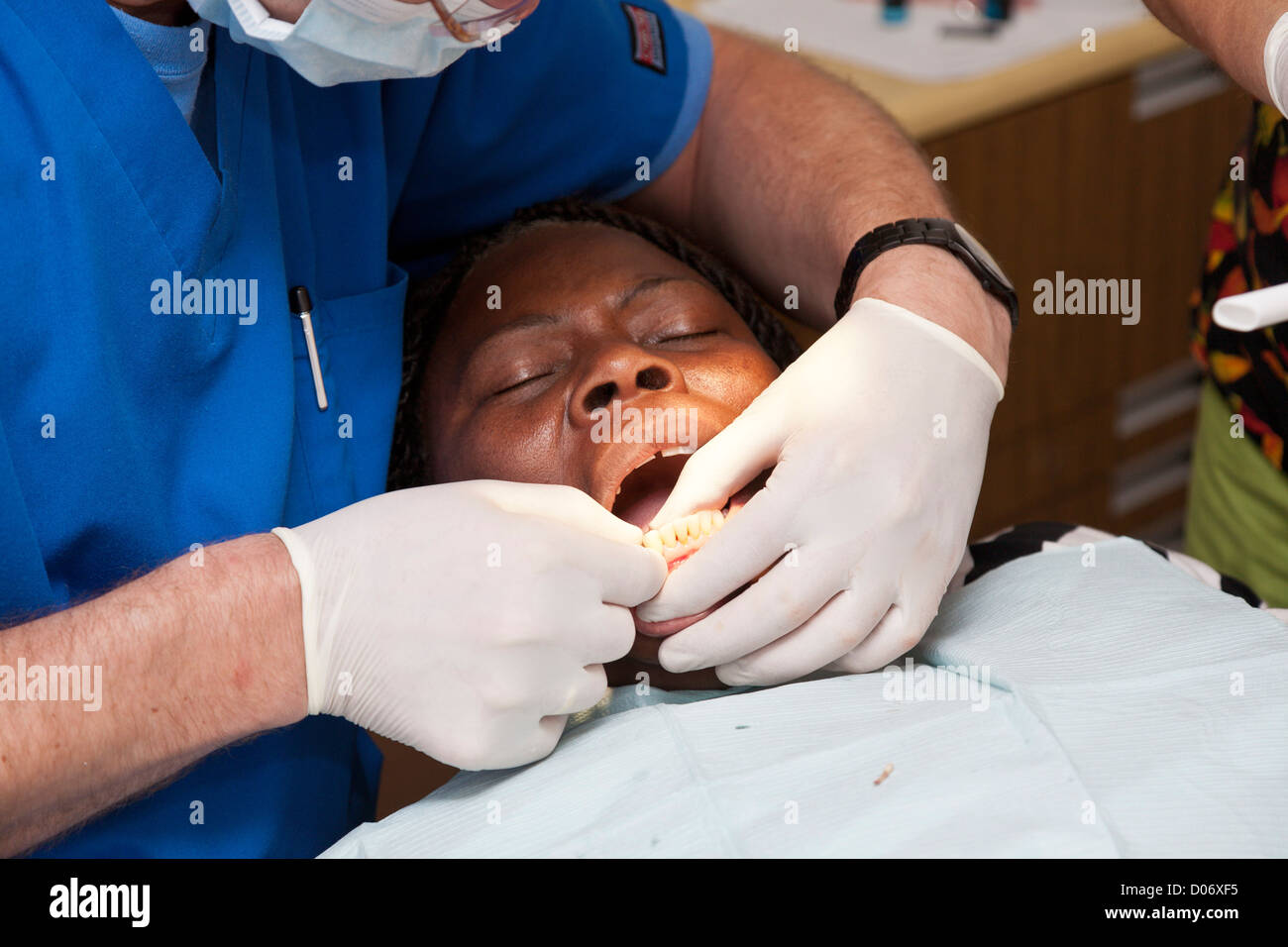 White male volunteer dentist and assistant provide services for black woman through Mission Smiles mobile clinic in Tampa, FL Stock Photo