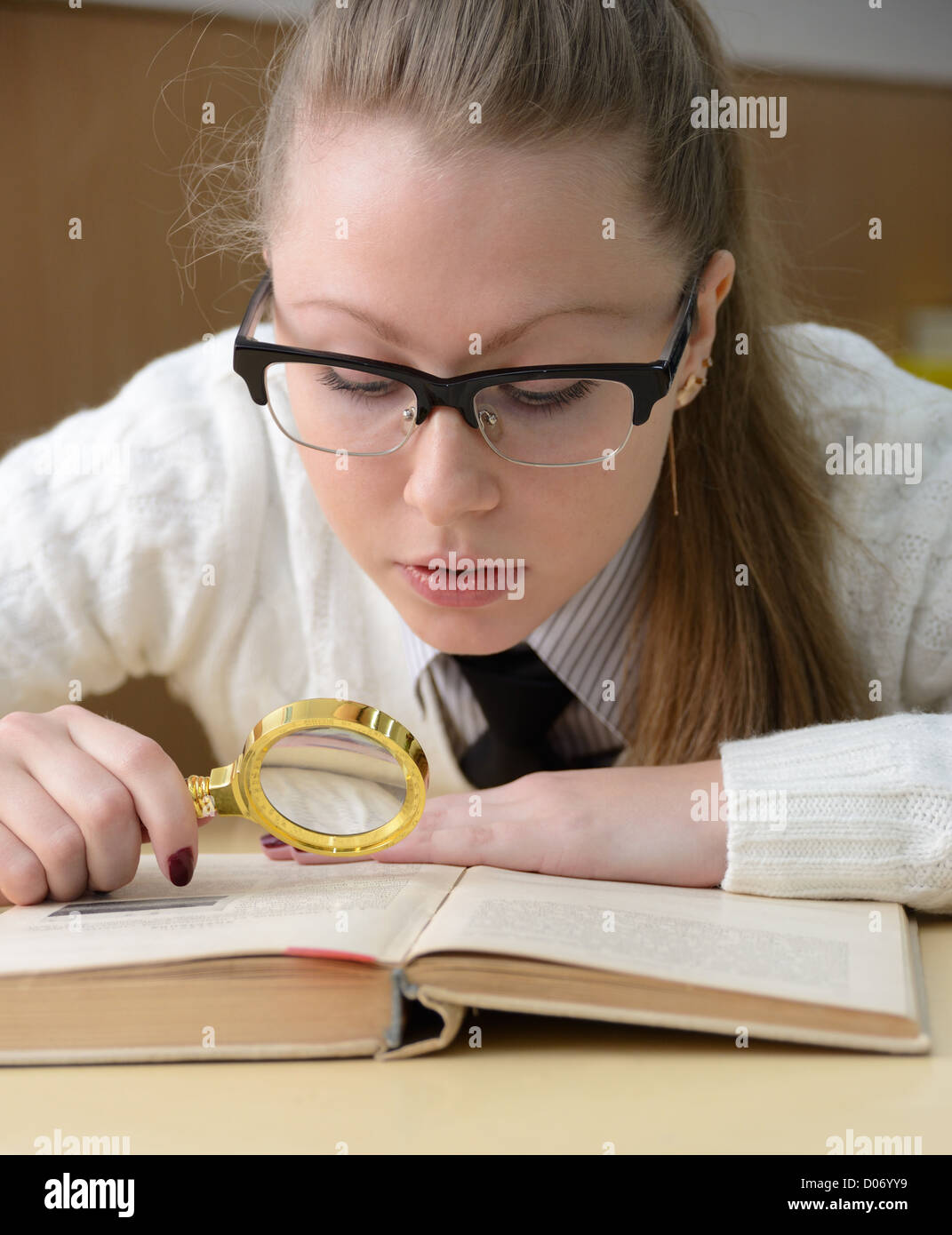 woman reading a book with a magnifying glass Stock Photo