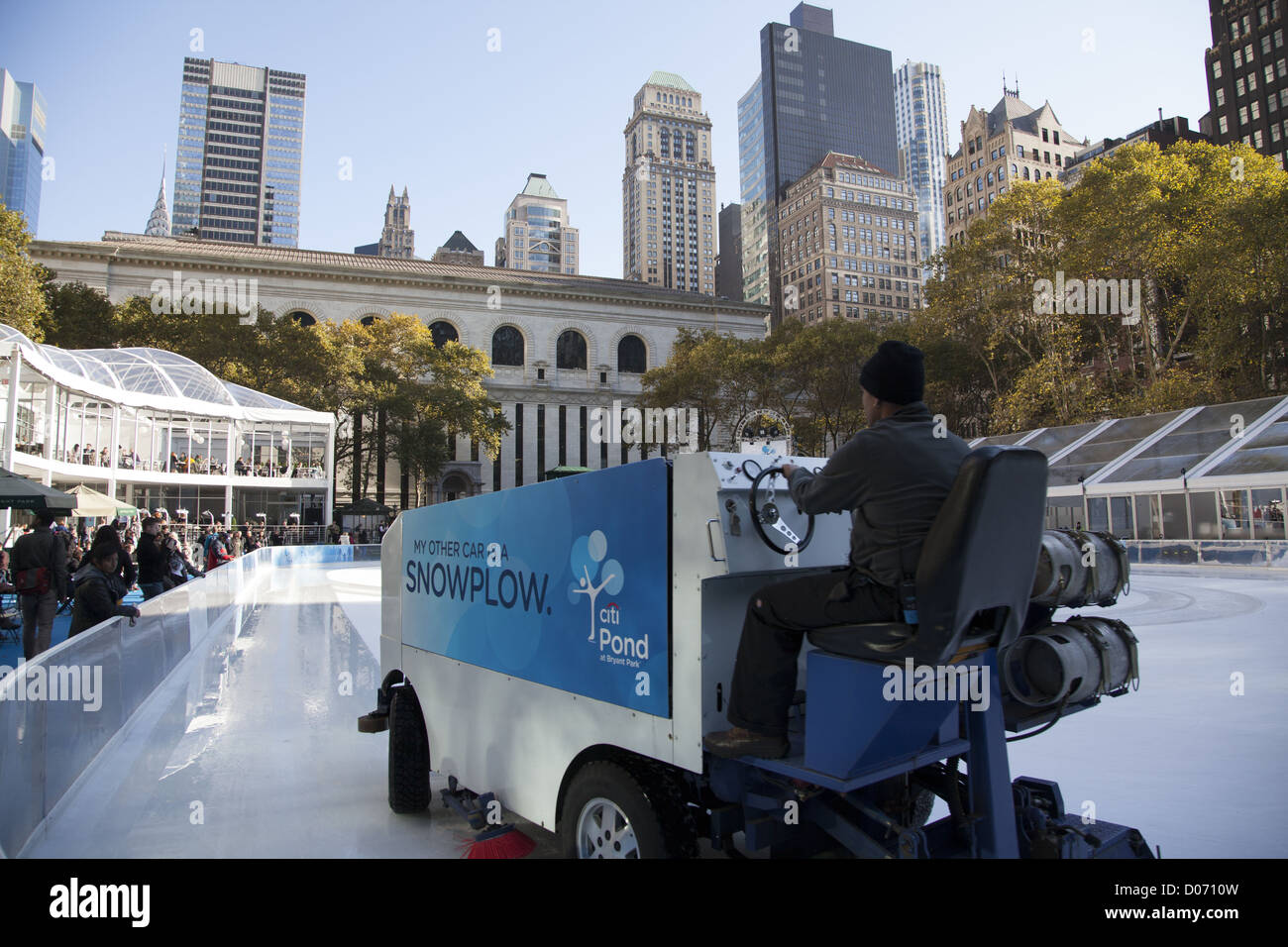 Worker smooths the ice at the skating rink in Bryant Park. NY Public Library in the background