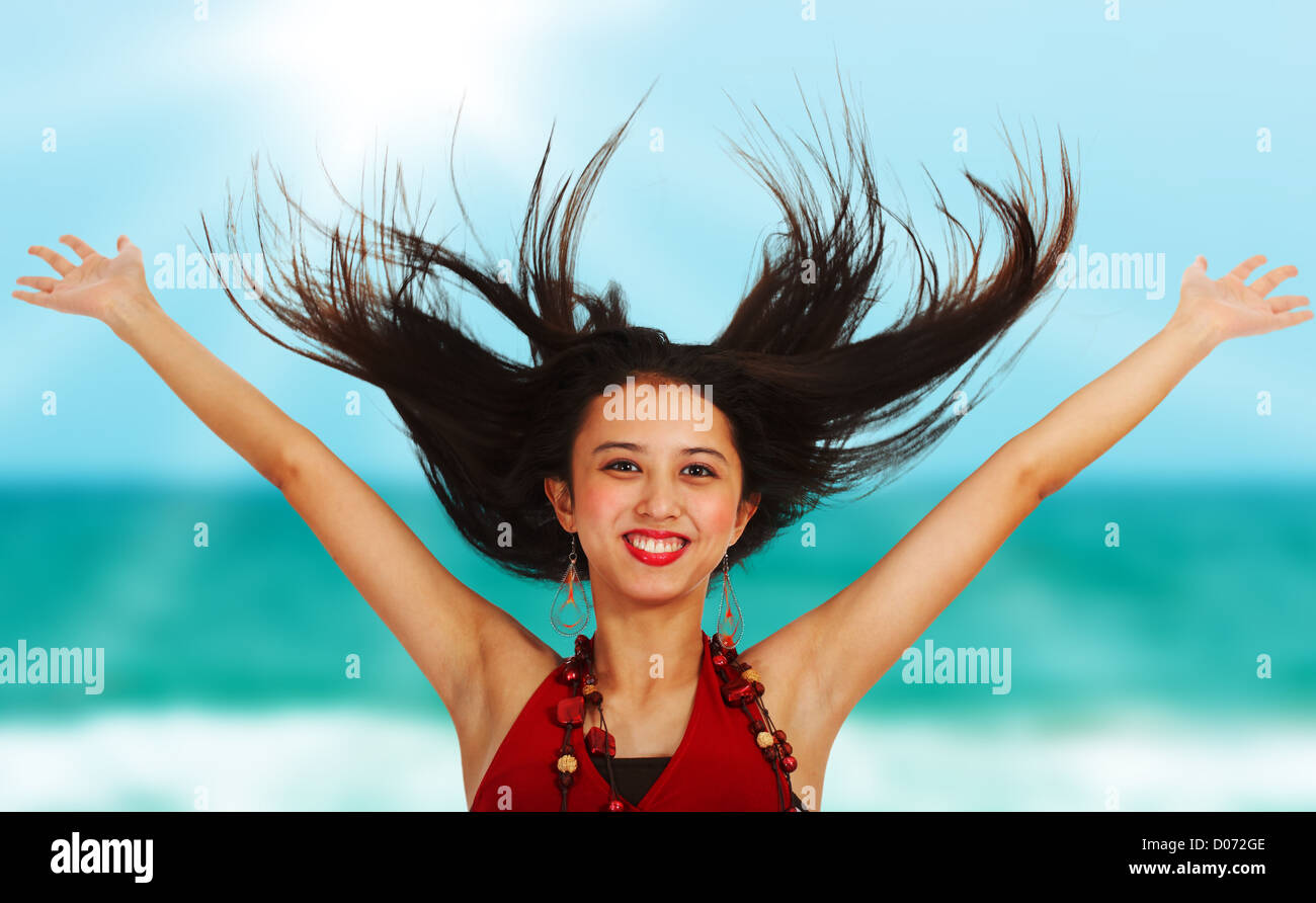 Excited girl at the beach throwing her arms in the air Stock Photo
