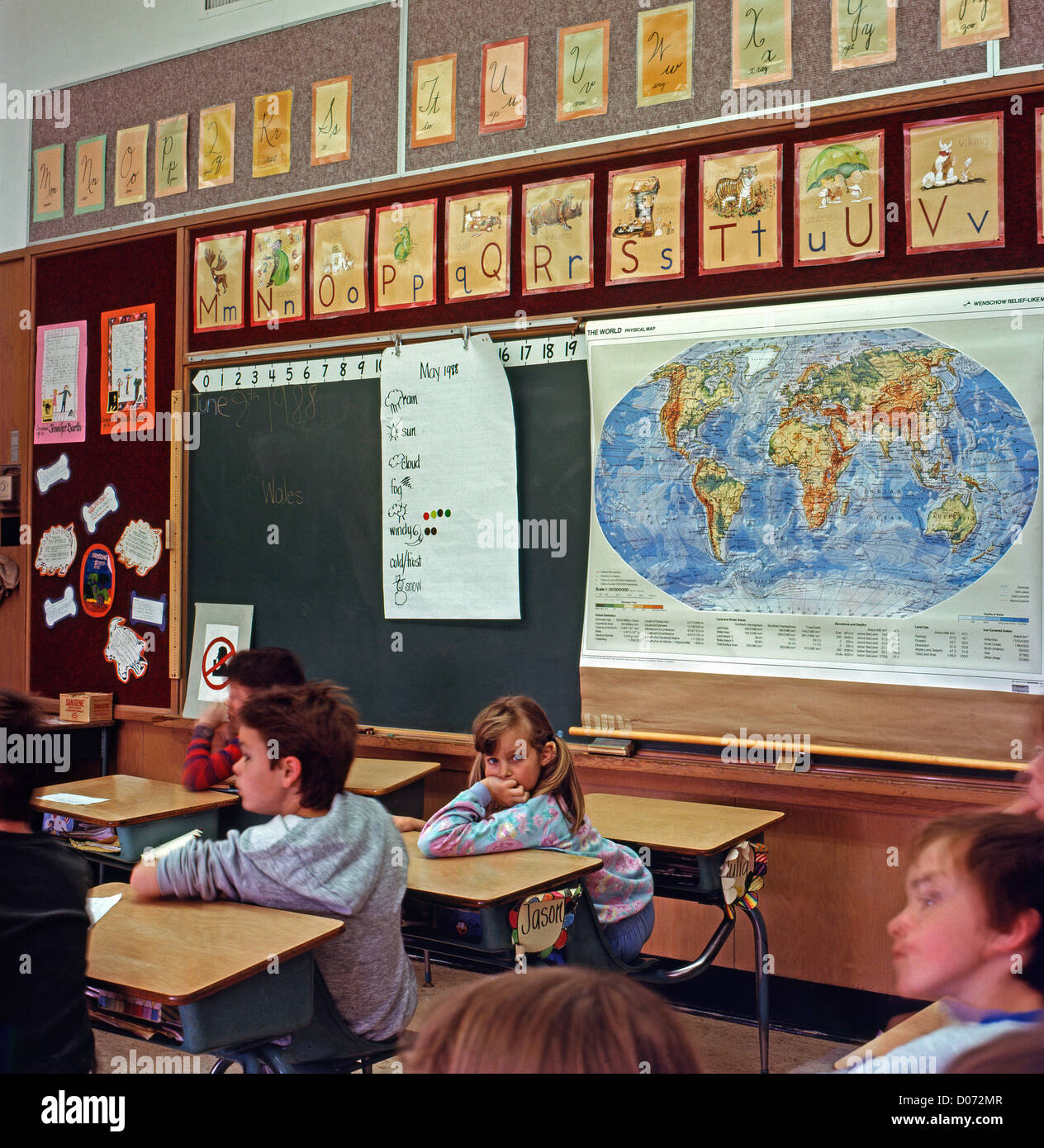 Elementary schoolchildren sitting at their desks in a 90s classroom with a map or the world Lantzville, British Columbia Canada   KATHY DEWITT Stock Photo