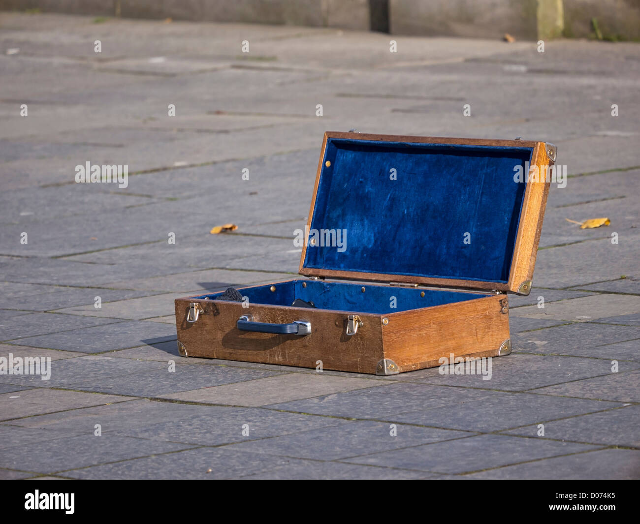 An old wooden box used by a street busker for collecting money for his performance. On the street in Edinburgh, Scotland. Stock Photo