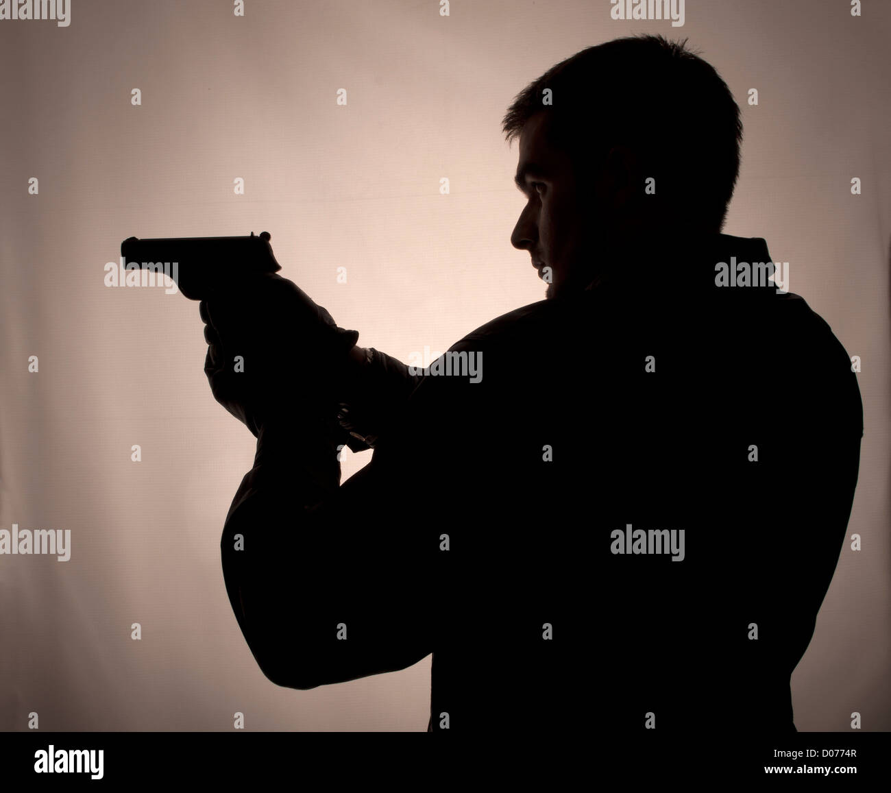 Silhouette of a man holding a gun Stock Photo