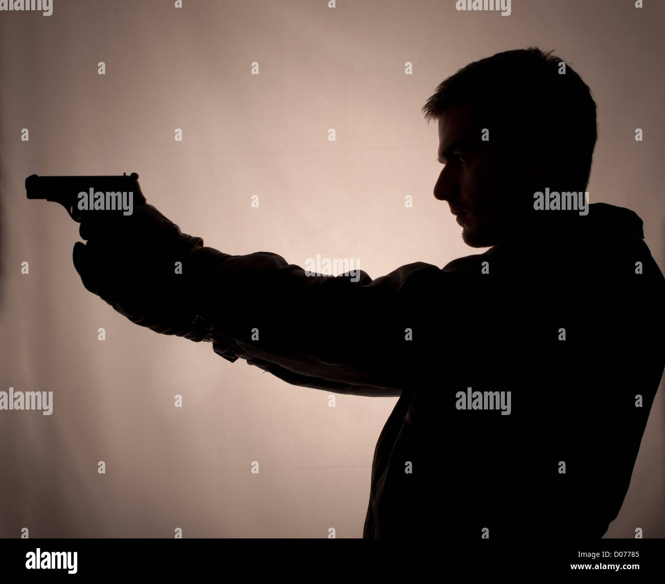 Silhouette of a man holding a gun Stock Photo