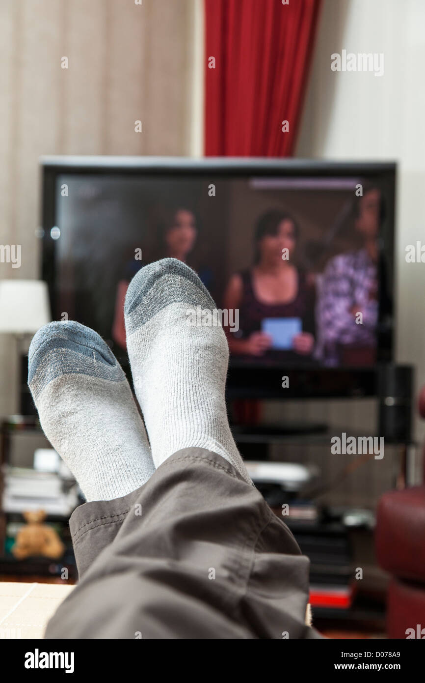 Male relaxing and watching television while wearing socks. Feet are in