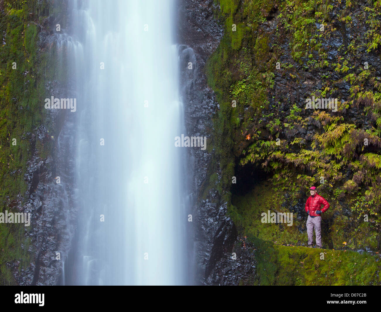 USA, Oregon. A man in red stands aside Tunnel Falls in a fall color