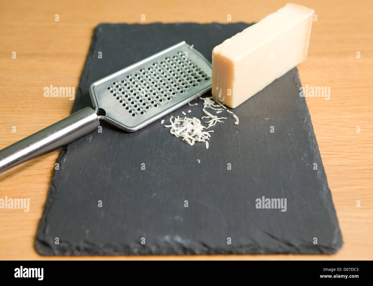 A block of Parmesan with a cheese grater on a slate plate Stock Photo -  Alamy