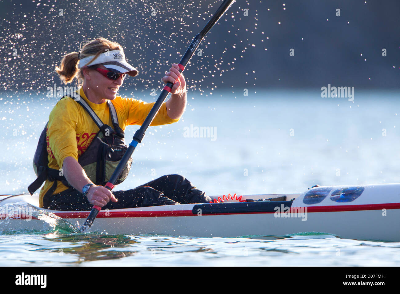 USA, Washington State. A woman kayaker races her high-performance surf ski kayak on a inland waterway. (MR) Stock Photo