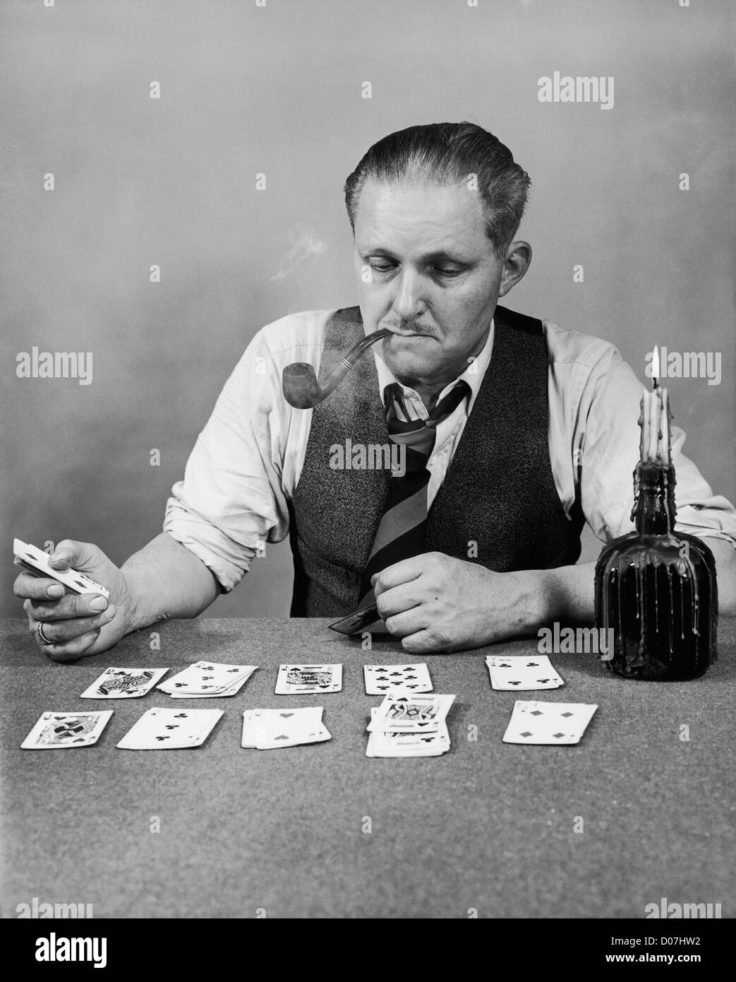 Man playing solitaire and smoking a pipe Stock Photo