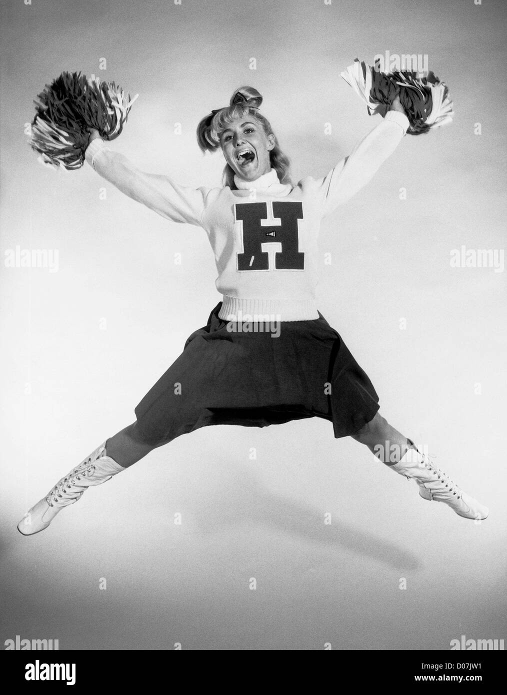 Cheerleader with pom-poms jumps in the air Stock Photo