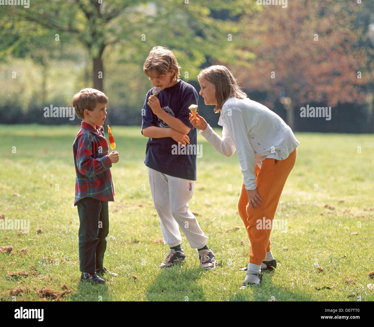Brother and sisters in park, with icecreams, Ascot, Berkshire, England
