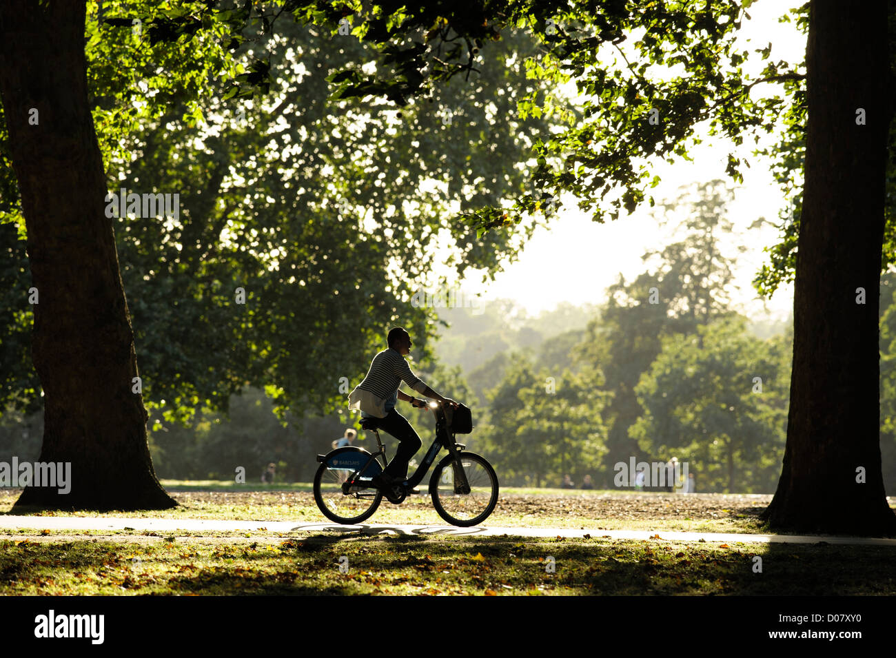 A young man cycles through Hyde Park on a "Boris Bike" (Hired Bike