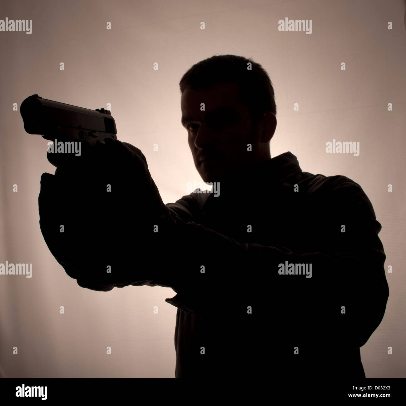 Silhouette of a man holding a gun Stock Photo