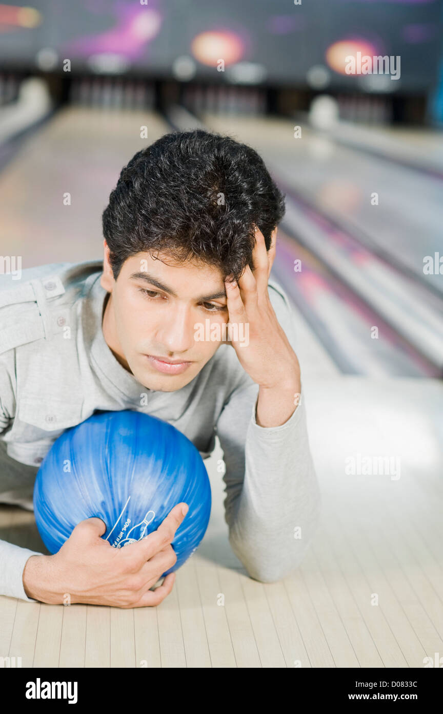 Young man lying with a bowling ball in a bowling alley Stock Photo Alamy