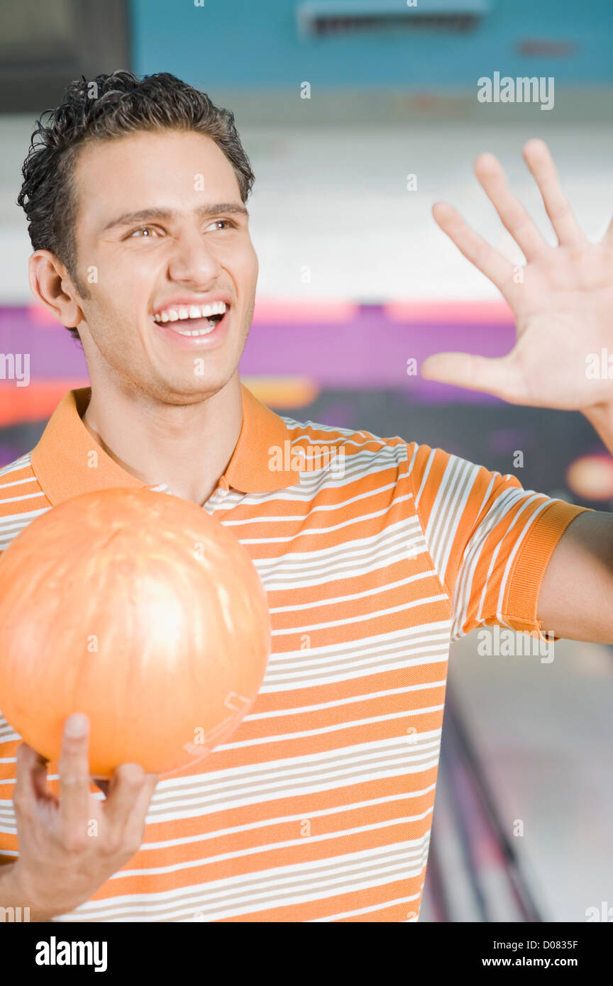 Young man holding a bowling ball and gesturing in a bowling alley Stock