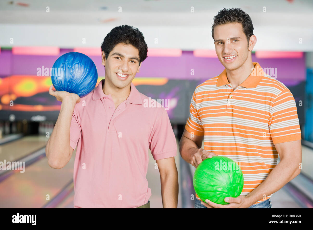 Two young men holding bowling balls in a bowling alley Stock Photo Alamy
