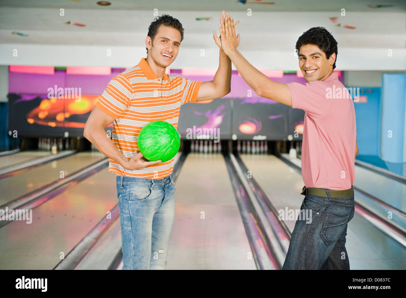 Two young men giving highfive in a bowling alley Stock Photo Alamy