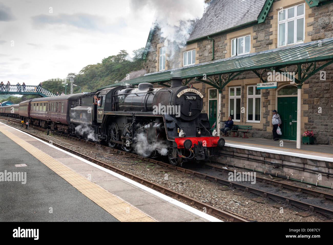 The Cambrian steam train approaches Machynlleth railway station platform pulling some passenger coaches for coastal rail trip Stock Photo