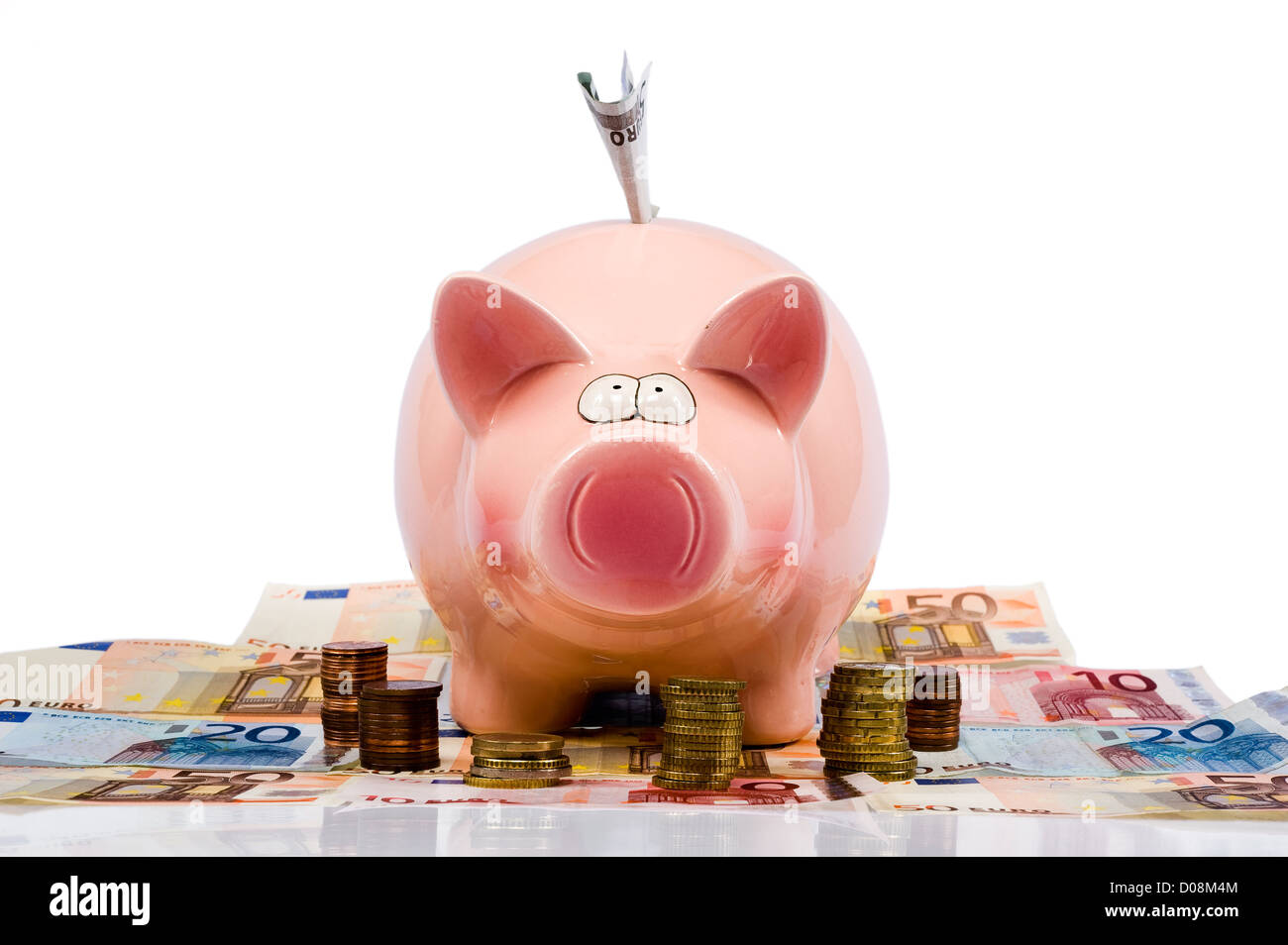 A full saving pig is standing between euro paper money and coins Stock Photo