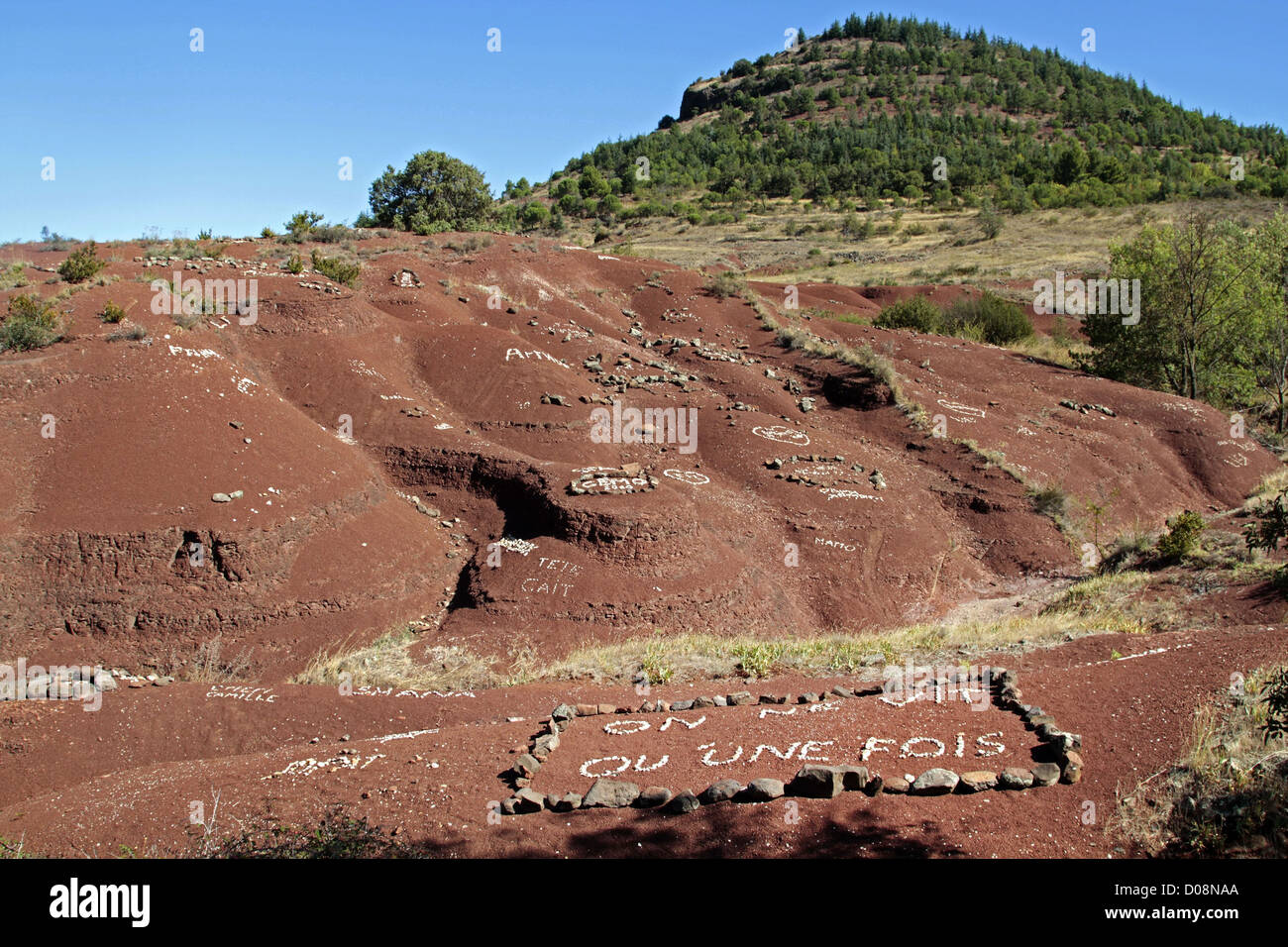 INSCRIPTION OF WHITE STONES WE ONLY LIVE ONCE ON THE RED CLAY RICH IN IRON OXIDE THE RED EARTH NEAR LAKE SALAGOU HERAULT (34) Stock Photo