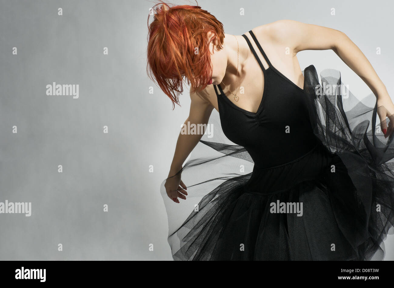 Beautiful ballerina wearing black tutu dancing over textured gray