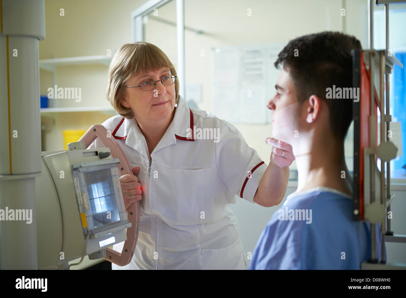 teenage boy patient in X Ray department with nurse and radiographer preparing him for an X Ray Stock Photo