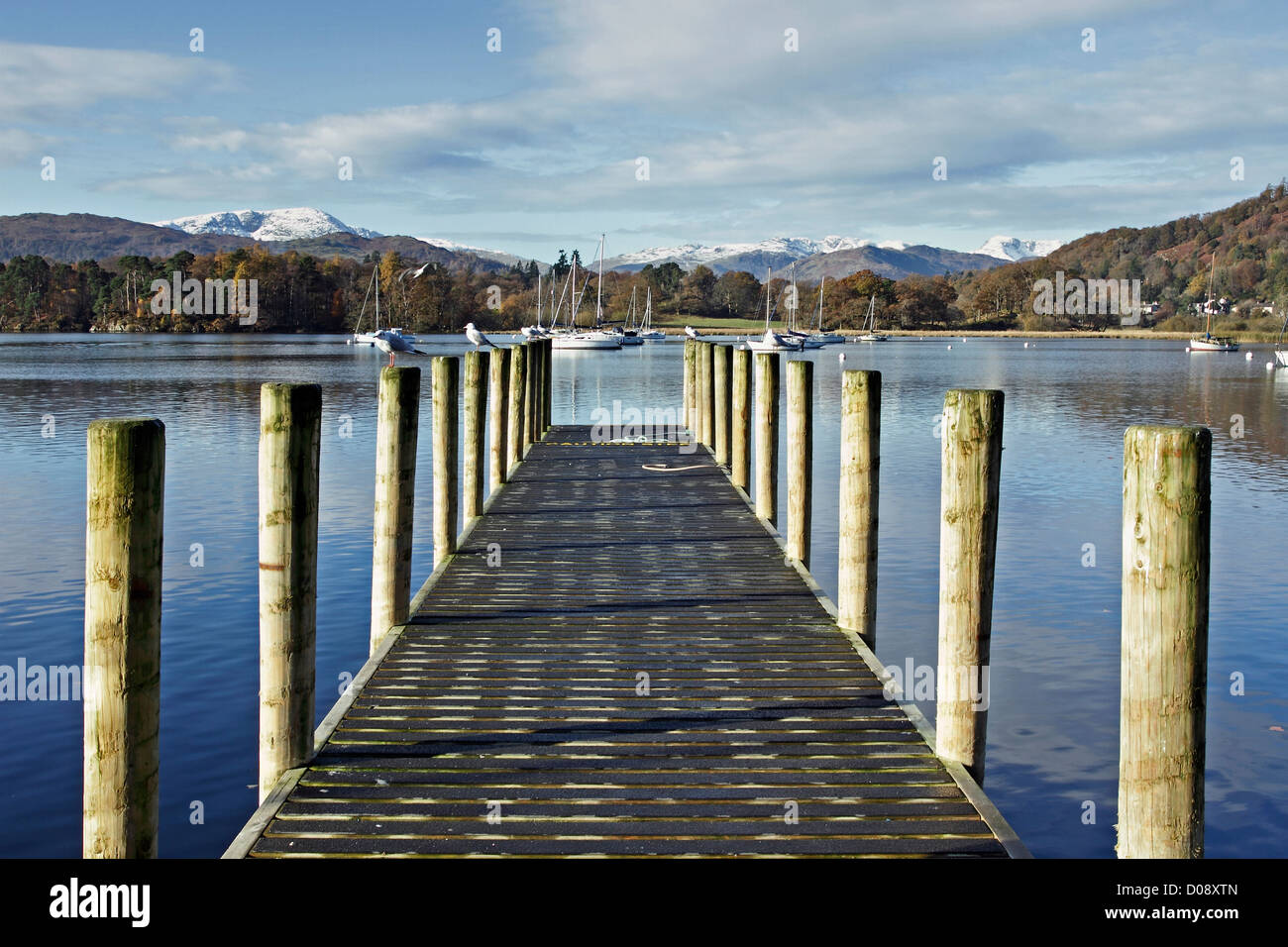 A mooring jetty at Waterhead, Ambleside on Lake Windermere with snow on the distant fells Stock