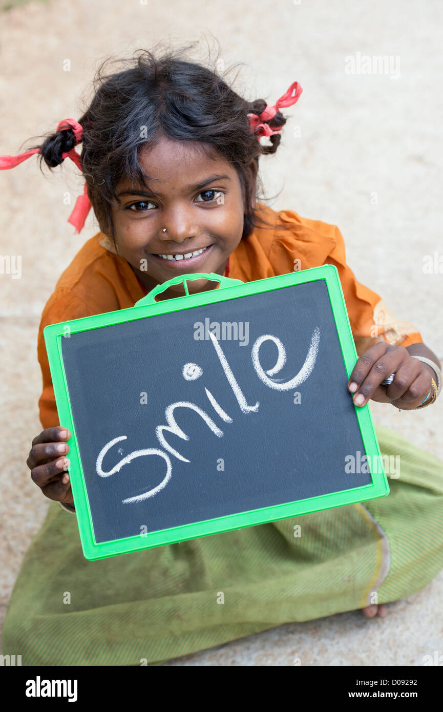 Happy Indian street girl holding a chalkboard with SMILE written on it.  Andhra Pradesh, India Stock Photo