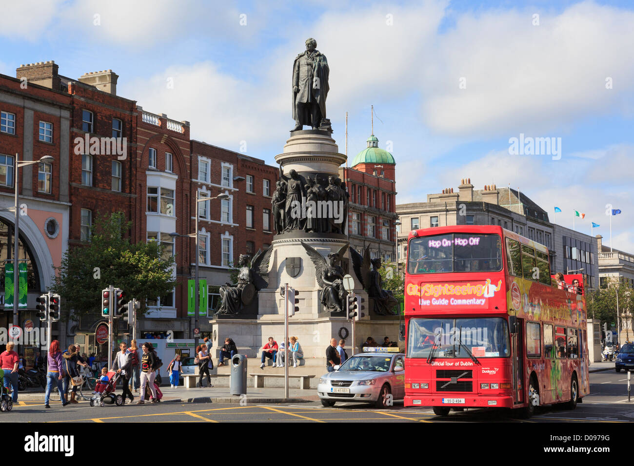 Red double decker Hop on Hop off city sightseeing tour bus passing Daniel O'Connell Monument on street. Dublin city Ireland Eire Stock Photo