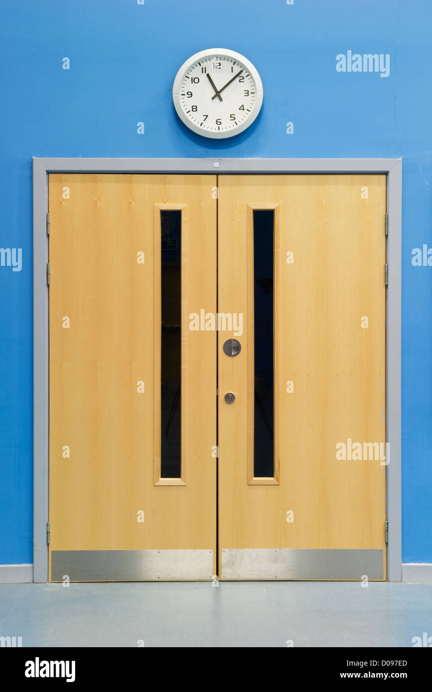 Clock above double doors in the main hall of a secondary school Stock