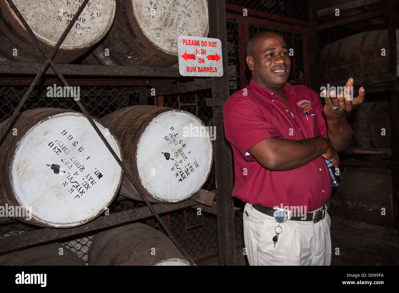 GUIDE GIVING EXPLANATIONS TO TOURISTS IN FRONT OF BARRELS OF RUM AT THE