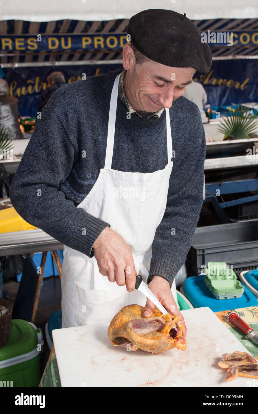 POULTRY SELLER CUTTING UP A CHICKEN IN THE MARKET IN VIC-EN-BIGORRE HAUTES-PYRENEES (65) MIDI-PYRENEES FRANCE Stock Photo