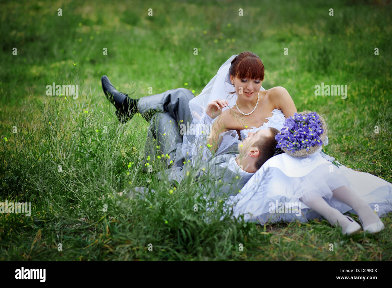 Happy wedding couple resting on fresh green grass Stock Photo - Alamy