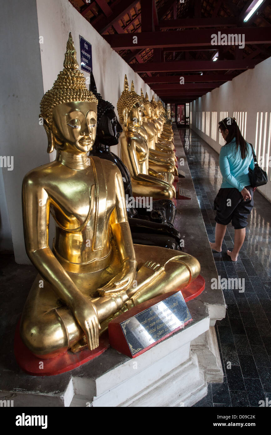 THAI WOMAN LOOKING AT THE STATUES OF BUDDHA EXHIBITED INSIDE THE WAT PHRA SI RATANA MAHATHAT TEMPLE PHITSANULOK THAILAND ASIA Stock Photo