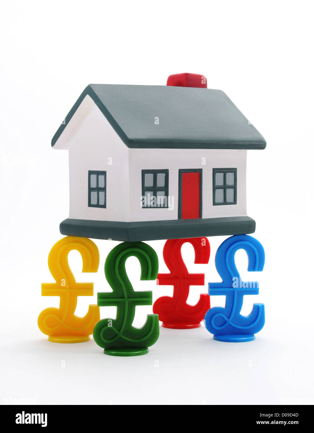 HOUSE BALANCED ON BRITISH POUND SIGNS RE HOUSE PRICES HOUSING PROPERTY MARKET MORTGAGES VALUES BUYERS SELLERS FIRST TIME SAVINGS Stock Photo